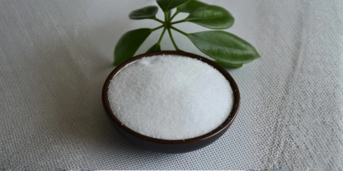 White crystalline sodium citrate powder in a small bowl, representing a food and pharmaceutical buffering agent